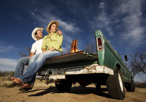 Portrait of Cowboy and woman on pickup truck bed