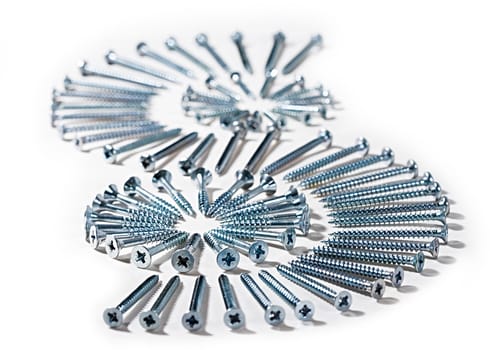 Picture made of screws different sizes on a white textile, metal and cloth.

