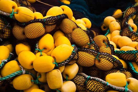 Closeup on fishing net with yellow floaters stored on fisher boat during the day