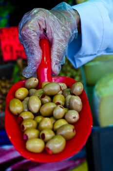 Hand wearing gloves and presenting filled green olives at Egypt Bazaar (MisirCarsisi) in Istanbul, Turkey