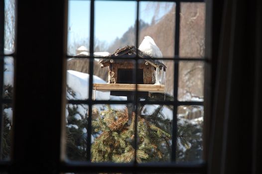 Shot of birdhouse through window in austrian winter.