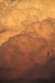 A detail of cumulonimbus clouds with the evening colors cast abone them.