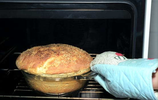 Taking out potato bread from oven with muffle 