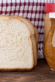 Yellow jam in bank and a white bread for a sweet sandwich.