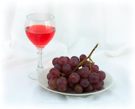 Still-life with a glass of red wine and grapes on a white background