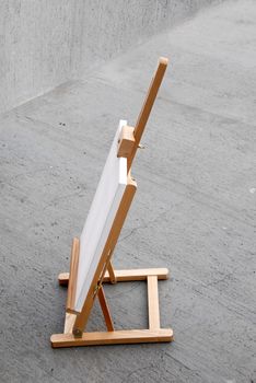 Easel with blank canvas on gray concrete background