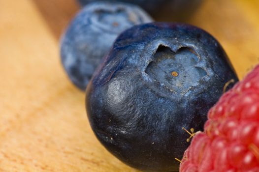 A couple of fresh ripe rasberry and blueberry on the wooden plate