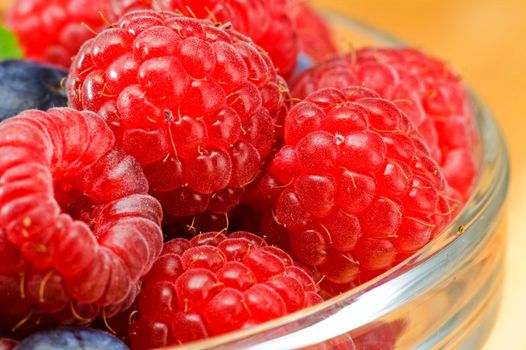 Fresh ripe raspberry and bluberry in glass jam-dish