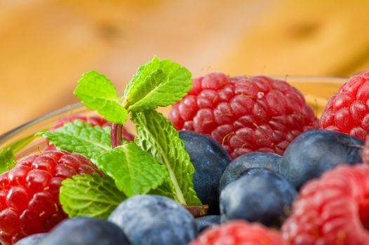 Fresh ripe raspberry and bluberry in glass jam-dish