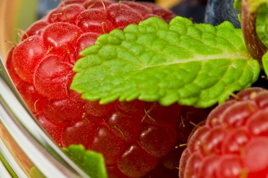 Fresh ripe raspberry and bluberry in glass jam-dish