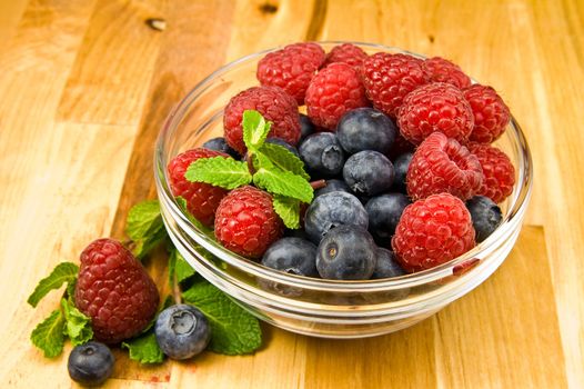 Fresh ripe raspberry and bluberry in glass jam-dish