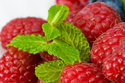 Fresh ripe raspberry and blueberry with green mint leaves 