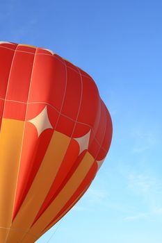 Vivid orange hot air balloon in the blue sky.