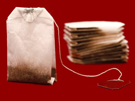 three white teabags over the dark red background