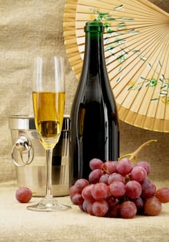 Still life with champagne bottle, bucket, goblet and grapes