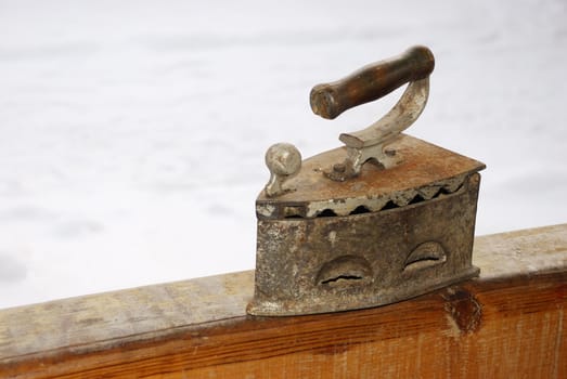 Old iron on a timber outside with snow in background.