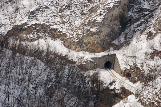 Tunnel in a hill and car trails in snow.