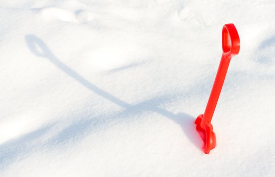 small red children shovel into a snow with shadow