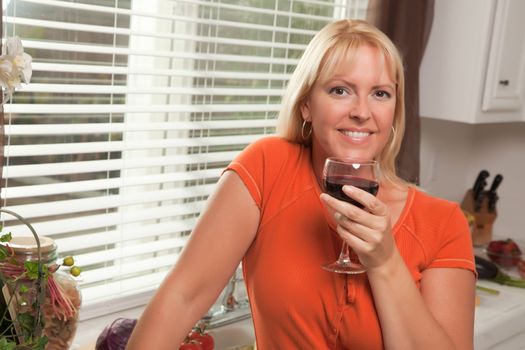 Attractive Blond with a Glass of Wine in the Kitchen