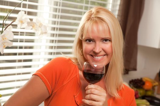 Attractive Blond with a Glass of Wine in the Kitchen