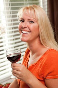 Attractive Blond with a Glass of Wine in the Kitchen