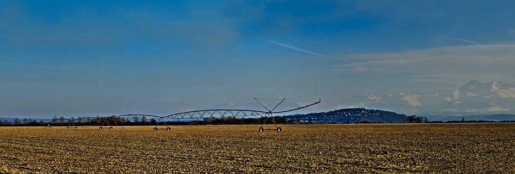 HDR Paronamic view of a corn field in winter with irrigation system and the Pyrenees mountains on the background