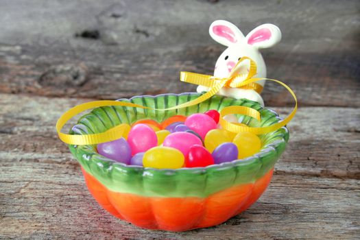 Easter bunny candy dish full of jelly beans and isolated on a wood textured background.