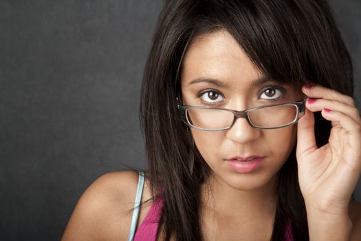 Close up portrait of a pretty brunette woman looking over her glasses