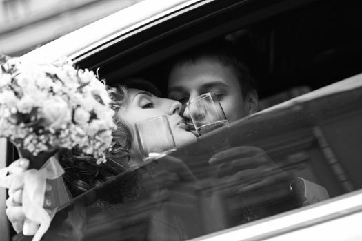 Newly-married couple in car with champagne