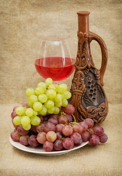 Ceramic brown bottle, grapes and red wine on canvas