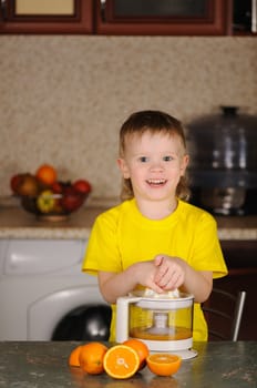 The child in a yellow vest to wring out juice  from an orange