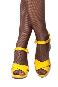 Feminine legs in yellow loafer on white background