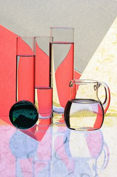 Glass glasses and jug on a multi-coloured background