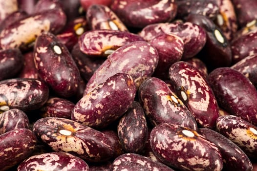 A couple of dark red and spotted kidney beans in wooden dish 