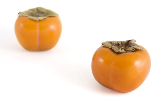 Two persimmons (sharon fruit) isolated on white background.  Fruit in foreground has clipping path