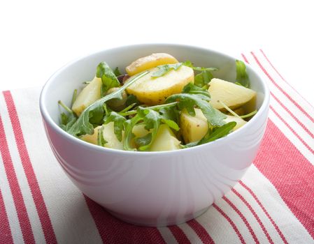 Gourmet potato salad with rocket lettuce, on red and white tablecloth
