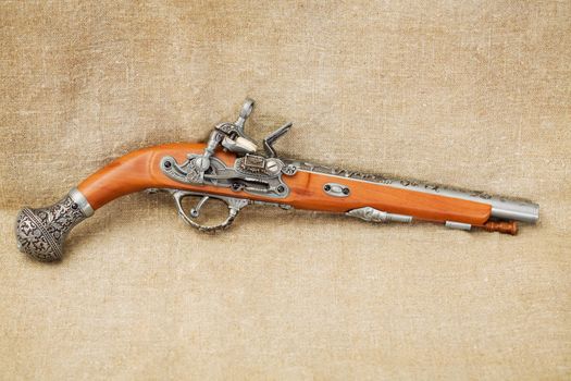 The ancient pistol on background brown canvas