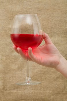 Wineglass of wine on female hand canvas background