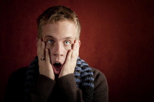 Shcoked young man with hands up to his face