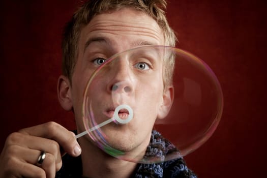 Handsome young blonde man blowing a bubble
