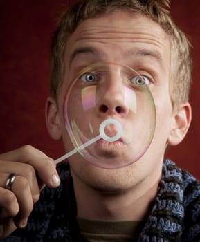 Handsome young blonde man blowing a bubble