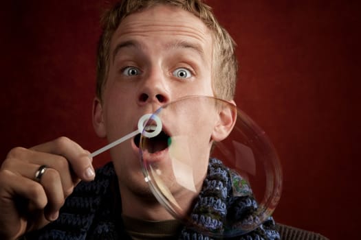 Handsome young blonde man blowing a bubble