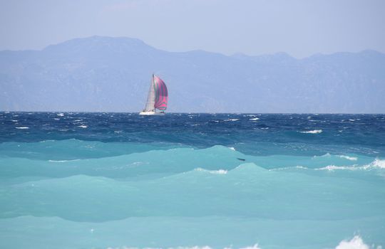 Sailboat sailing on the Mediterranean Sea with mountain backdrop