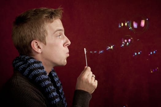 Handsome young blonde man blowing a bubbles