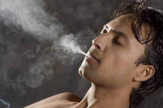 Close-up of an intensively smoking man with heavy smoke