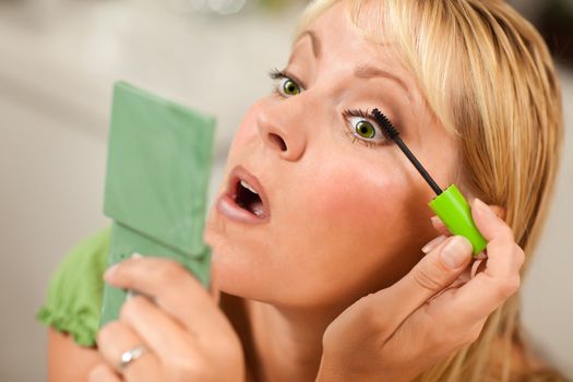 Blonde Woman Applying Her Mascara Makeup in Her Bathroom.