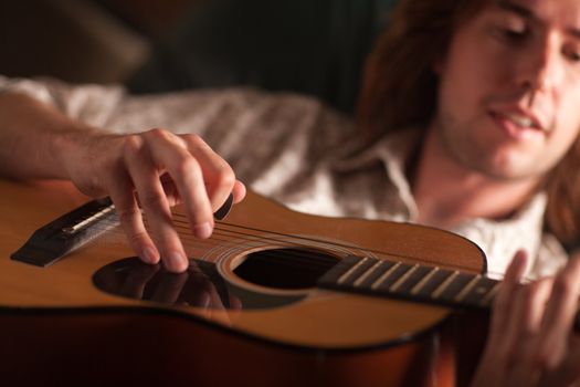 Young Musician Plays His Acoustic Guitar under Dramatic Lighting.