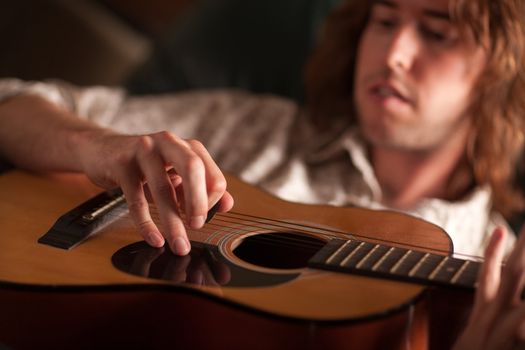 Young Musician Plays His Acoustic Guitar under Dramatic Lighting.