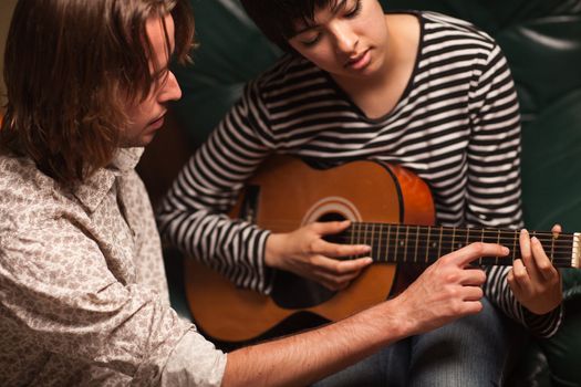 Young Male Musician Teaches Female Student How To Play the Guitar.