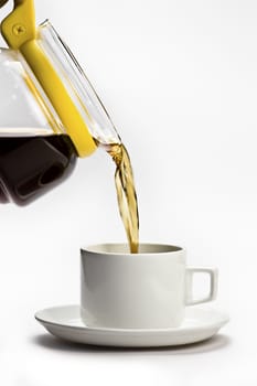 A transparent teacup with yellow handle and black herbal tea  white cup